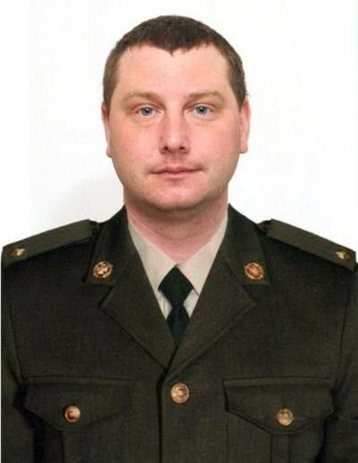 Портрет чоловіка у військовій формі зеленого кольору із сорочкою та краваткою на білому тлі. 