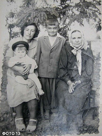 Архівна чорно-біла сімейна фотографія: жінка тримає на руках маленьку дитину, поруч стоїть хлопчик у піджаку, а праворуч сидить літня жiнка у хустці. 