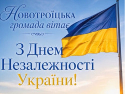 Вітальна листівка до Дня Незалежності України. На тлі блакитного неба та золотого пшеничного поля із соняшниками майорить Державний Прапор України на флагштоці. Ліворуч розміщено напис: «Новотроїцька громада вітає з Днем Незалежності України!»