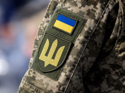 Український військовий у формі з прапором України та гербом-тризубом на рукаві.