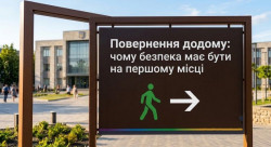 На зображенні, зробленому вдень у сонячну погоду, великим планом показано коричневий інформаційний знак на двох металевих стовпах. На ньому білими літерами написано українською мовою: 